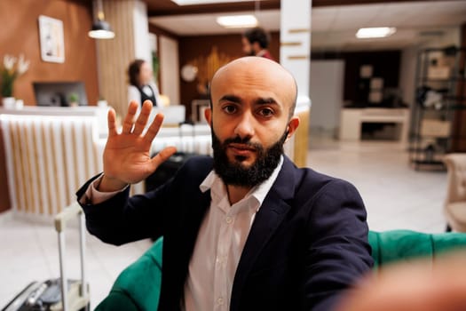 POV of middle eastern man on telework call, sharing new strategy plans with executive manager in lounge area at hotel. Young entrepreneur attending videocall meeting in lobby, business trip.