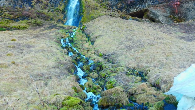 River stream from scandinavian cascade flowing down off of hill, water flow running off cliff in iceland. Beautiful seljalandsfoss waterfall in reykjavik, arctic landscape. Handheld shot.