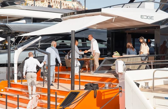 Monaco, Monte Carlo, 29 September 2022 - Invited wealthy clients inspect mega yachts at the largest fair exhibition in the world yacht show MYS, port Hercules, yacht brokers, sunny weather. High quality photo