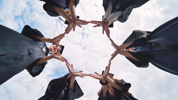 College graduates make a circle of their hands