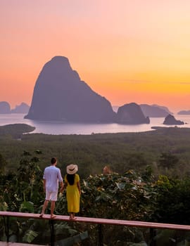 A couple of men and woman watching the sunrise at Sametnangshe viewpoint in Phangnga Bay with mangrove forest and limestone cliffs in the Andaman Sea, Sametnangshe Phangnga Thailand