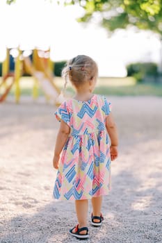 Little girl is walking on the playground. Back view. High quality photo
