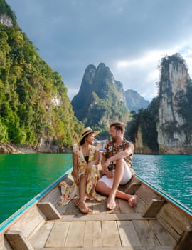 A couple of men and women in front of a longtail boat in Khao Sok Thailand, Scenic mountains on the lake in Khao Sok National Park South East Asia at sunset