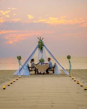 Romantic dinner on the beach in Pattaya Thailand, a couple man and woman mid age Asian woman, and a European man having dinner on the beach in Thailand during sunset.