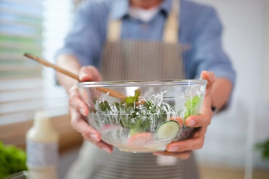 Closeup senior man holding bowl of healthy fresh vegetarian salad. Healthy food, dieting, vegan food concept