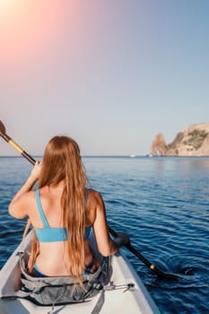 Woman in kayak back view. Happy young woman with long hair floating in transparent kayak on the crystal clear sea. Summer holiday vacation and cheerful female people relaxing having fun on the boat