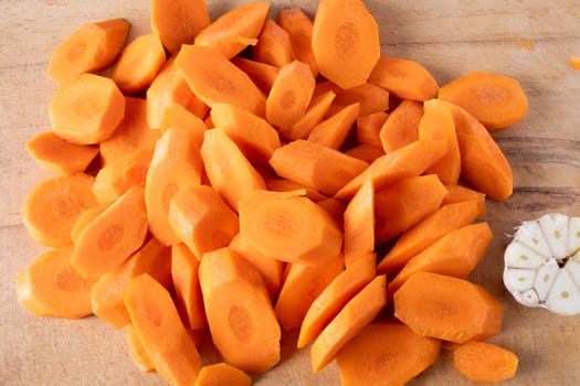 Fresh raw carrots cut into pieces lie on a cutting board. Selective focus.