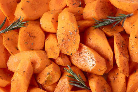 Fresh carrots cut into pieces, seasoned with spices and olive oil, lie on baking tray. Food background. Selective focus.