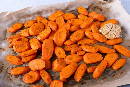 Baked carrots with spices on a baking tray. Selective focus.