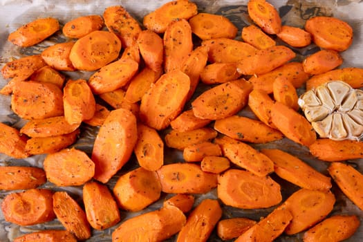 Baked carrots with spices on a baking tray. Selective focus.