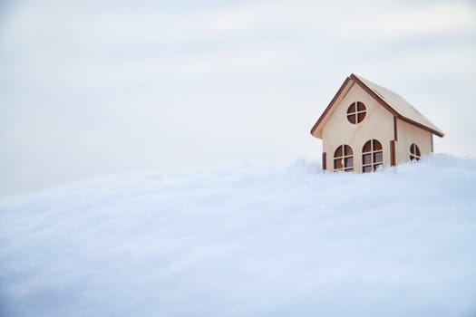 Wooden toy house on snow, natural abstract background. winter season concept. symbol of cozy, loving family home. construction, sales, rental concept. Christmas and new year holidays. copy space