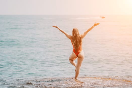 Woman sea yoga. Back view of free calm happy satisfied woman with long hair standing on top rock with yoga position against of sky by the sea. Healthy lifestyle outdoors in nature, fitness concept.