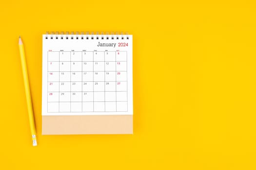 January 2024 desk calendar and wooden pencil on yellow color background. Time planning, day counting and holidays.