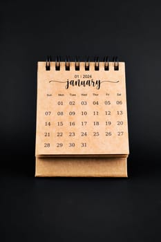 2024 January brown desk calendar on black background.