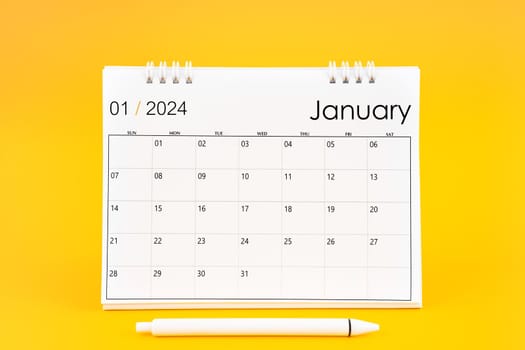 January 2024, Monthly desk calendar for 2024 year and pen on yellow color background.