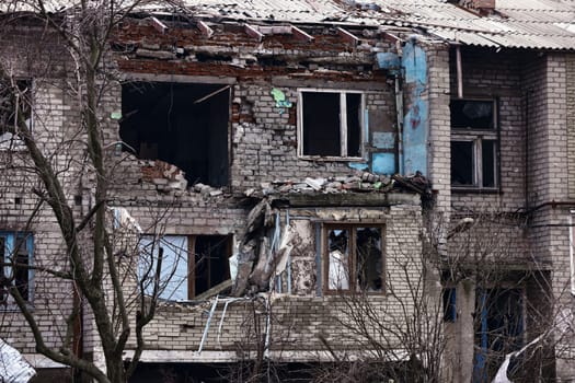 An apartment building in a war zone. Damage to a house as a result of artillery shelling. War in residential areas, broken windows and burned apartments. Armed conflict in Ukraine.
