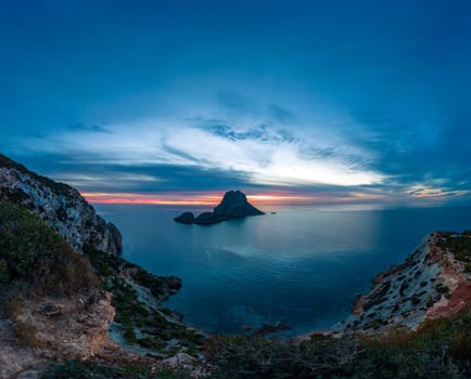 Picturesque sunset with vivid hues over a calm ocean and solitary island.