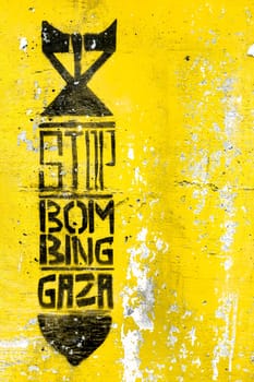 Graffiti on the yellow grungy wall depicting the silhouette of a bomb. Inside message: STOP BOMBING GAZA. Copy space. Fully editable.