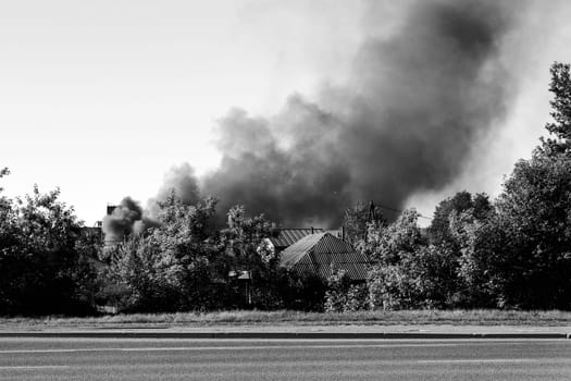 Fire in the city, from buildings and houses, black smoke. Black and white photo