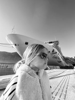 Little girl in sunglasses on the background of a cruise liner. Black and white photo. High quality photo