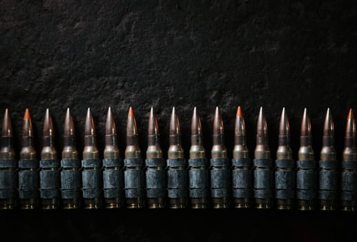 Machine gun bullet belt on the floor. Background on the military theme. Ammo, chain of ammo on concrete background. Top view of machine gun belt cartridge 7.62 mm caliber on dark background.
