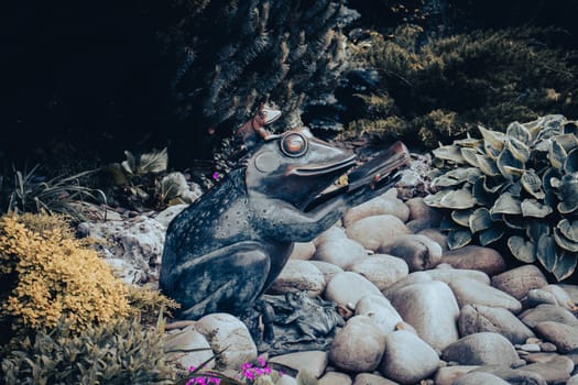 Bronze sculpture of a big frog reading a book, Kharkiv Central Park. Beautiful nature scenery photography. Idyllic garden scene. High quality picture for wallpaper, travel blog.