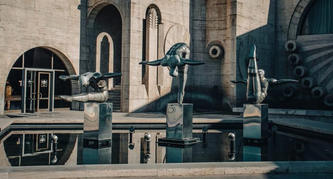 Modern art - stainless steel sculptures of three athletes in the pool concept photo. Statues on top of Cascades in front of entrance door to a museum in Yerevan. High quality picture for magazine, article