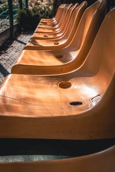 Close up yellow seats of tribune in public park concept photo. Chairs for audience in park. Cultural environment concept. Empty seats, modern stadium. High quality picture for wallpaper