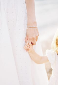 Little flower girl holds bride finger. Cropped. Faceless. High quality photo