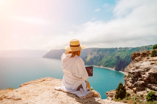 Freelance woman working on a laptop by the sea, typing away on the keyboard while enjoying the beautiful view, highlighting the idea of remote work