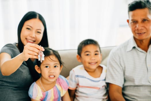 A joyful family poses with mother holding keys to their new house. Reflecting happiness togetherness and the anticipation of new beginnings in their home sweet home. New house