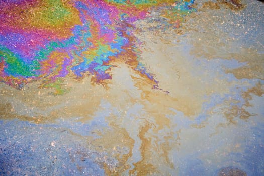 Petroleum fuel spilled on wet asphalt, abstract background.