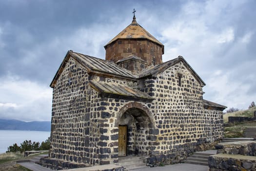 Monastery under dramatic spring sky photo. Ancient church near lake Sevan concept photo. High quality picture for wallpaper