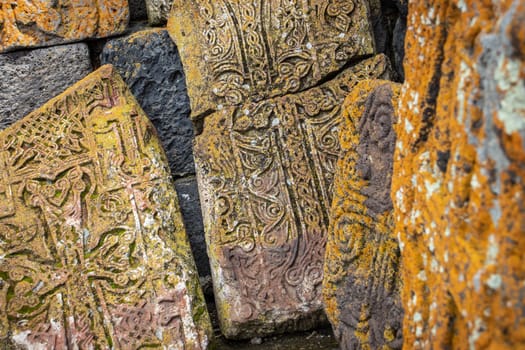 Close up stone cross with yellow lichen cover the rough stone concept photo. Historical tombs and head stones. Rocks full of the moss texture in nature for wallpaper.