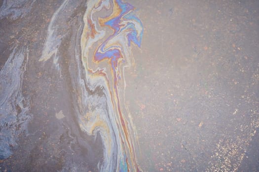 a marble texture of a rainbow spill of gasoline on a sidewalk in a puddle as a background