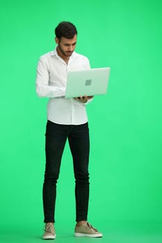 man on a green background. uses a computer.