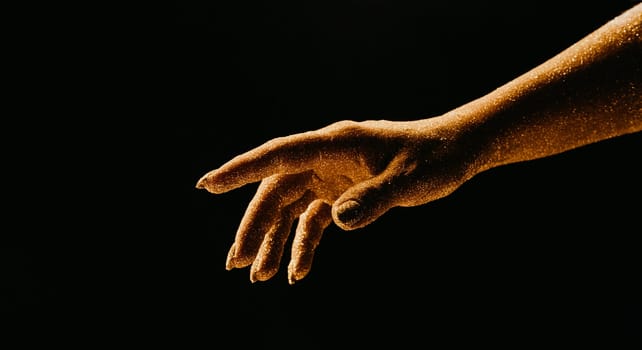 Golden glittering woman hand with dust or sand on black background. Shimmer, time, life moments, deadline, business management, educational creative content concept.