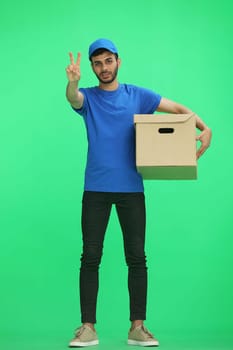 A man on a green background with box shows a victory sign.
