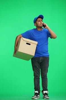 A man on a green background with box conversate on the phone.