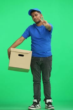 A man on a green background with box show a victory sign.