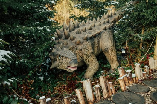 Bukovel, Ukraine - December 2023. Attraction statue of dinosaurs model in Dinopark, winter forest park in nature. Modern exhibition for children and adults. Education concept. High quality photo