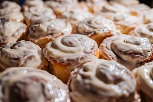 Close-up amazing fresh danish homemade baked cinnabon rolls buns with cream sauce. Sweet treat background. High quality photo