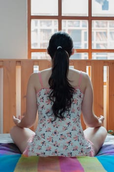 girl on her back sitting on her bed performing relaxation exercises in the morning with nightclothes. relaxation day. High quality photo