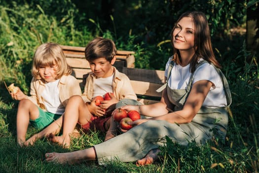 Woman gardener with kids children picked red apples in home countryside orchard. Happy young farmer style. Healthy lifestyle. High quality