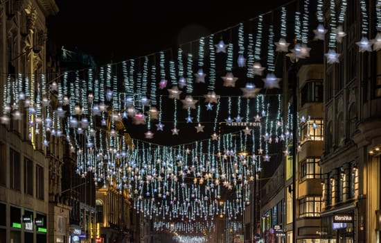 London, UK - Dec 25, 2023 - Christmas stars decoration led lights display. Dramatic view of the traditional Christmas decoration lights hanging above Oxford street during dusk, The Spirit of Christmas, Light Festival in London, Space for text, Selective focus.