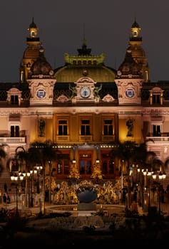 Monaco, Monte-Carlo, 12 November 2022: The famous square of Casino Monte-Carlo is at dusk, attraction night illumination, luxury cars, players, tourists, splashes of fountain. High quality photo