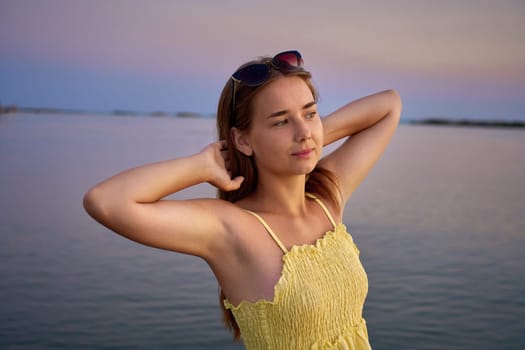 Young female traveler posing on the beach by the sea at sunrise and sharing her adventure travel.