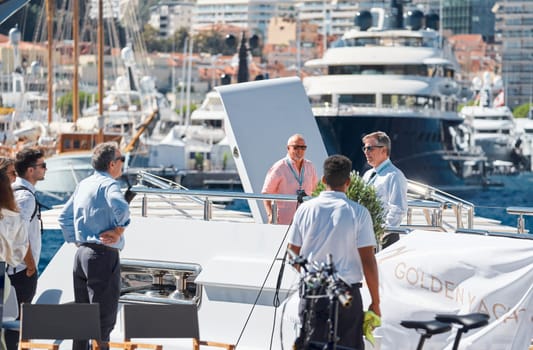 Monaco, Monte Carlo, 28 September 2022 - Invited wealthy clients inspect megayachts at the largest fair exhibition in the world yacht show MYS, port Hercules, yacht brokers, sunny weather. High quality photo