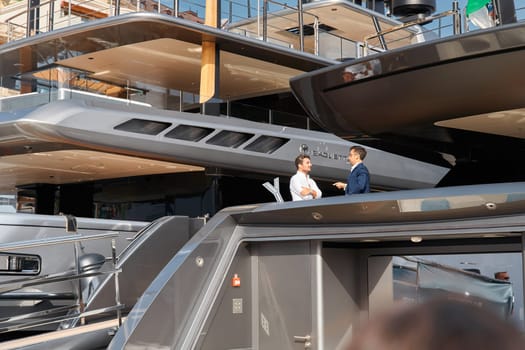Monaco, Monte Carlo, 29 September 2022 - Invited wealthy clients inspect mega yachts at the largest fair exhibition in the world yacht show MYS, port Hercules, yacht brokers, sunny weather. High quality photo