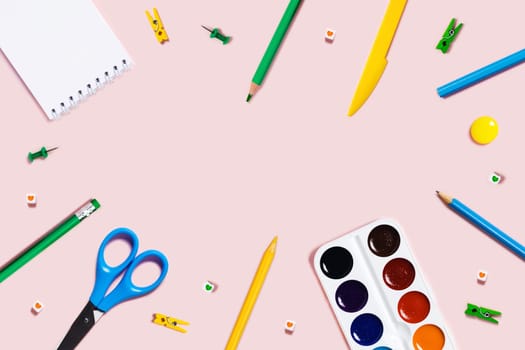 Back to school flat lay with colored pencils, watercolor, plasticine, and paper clips.